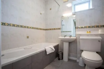 a bathroom with a tub and a toilet and a sink at Tredreath, Manor Cottages in Falmouth