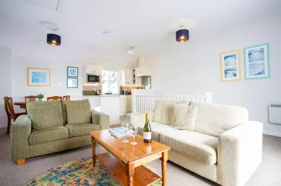 a living room with two couches and a wine bottle on a table at Tredreath, Manor Cottages in Falmouth
