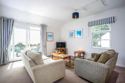 a living room with two chairs and a television at Tredreath, Manor Cottages in Falmouth