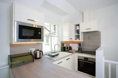 a white kitchen with a sink and a microwave at Tredreath, Manor Cottages in Falmouth