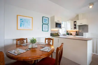 a kitchen with a wooden table with chairs and a kitchen counter at Tredreath, Manor Cottages in Falmouth