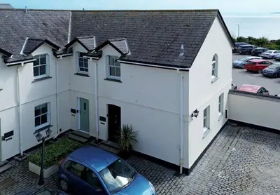 a car parked in front of a white house at Tredreath, Manor Cottages in Falmouth