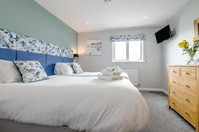 a bedroom with a large white bed with a blue headboard at 6 Bed in Winnards Perch oc-t29966 in Saint Columb Major