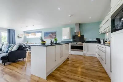 a kitchen with white cabinets and a living room at 6 Bed in Winnards Perch oc-t29966 in Saint Columb Major