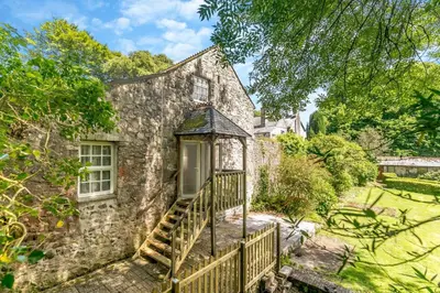 an old stone house with a wooden staircase in front of it at 1 Bed in Trewoon oc-t29505 in St Austell