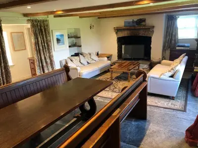 a living room with a couch and a fireplace at 17th Century Traditional Tintagel Farmhouse with Hot Tub in Treknow