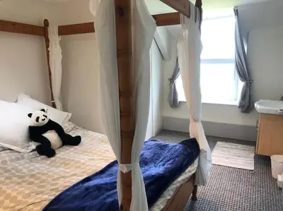a panda bear sitting on a bed in a bedroom at 17th Century Traditional Tintagel Farmhouse with Hot Tub in Treknow