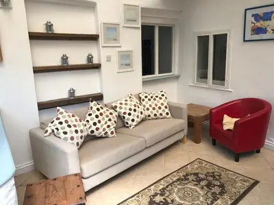 a living room with a couch and a red chair at 17th Century Traditional Tintagel Farmhouse with Hot Tub in Treknow