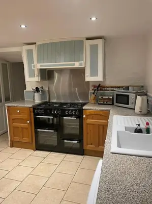 a kitchen with a stove and a sink at 17th Century Traditional Tintagel Farmhouse with Hot Tub in Treknow
