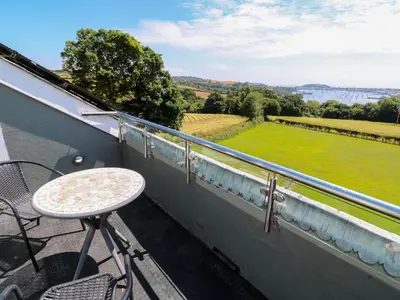 a balcony with a table and a view of a field at The Crows Nest in Falmouth