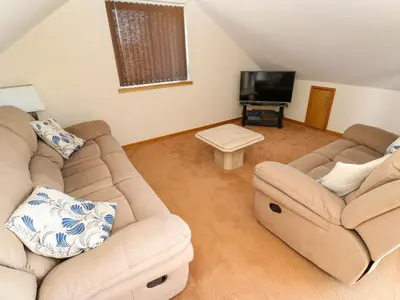 a living room with two couches and a flat screen tv at The Crows Nest in Falmouth