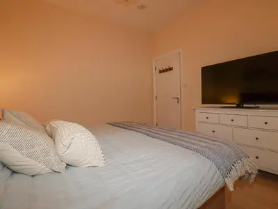 a bedroom with a bed with a flat screen tv at Serendib Cottage in Newquay