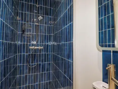 a bathroom with a shower with blue tiles at Serendib Cottage in Newquay