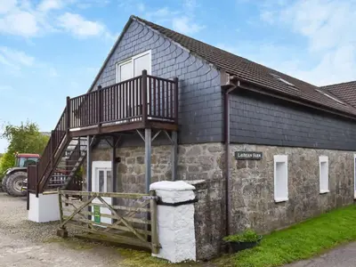 an old stone building with a balcony on it at Lavrean Farm in St Austell
