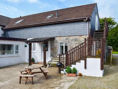 a cottage with a staircase and a picnic table at Lavrean Farm in St Austell