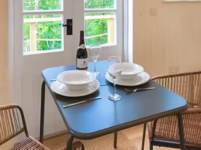a blue table with two plates and a bottle of wine at The Shepherds Hut At Rosewood House in Liskeard