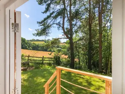 a view from the door of a yard with a fence at The Shepherds Hut At Rosewood House in Liskeard