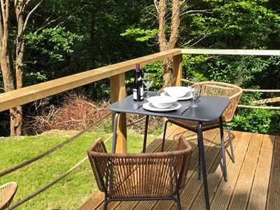 a black table and chairs on a wooden deck at The Shepherds Hut At Rosewood House in Liskeard