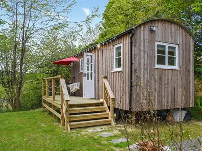 a wooden cabin with a porch and a deck at The Shepherds Hut At Rosewood House in Liskeard