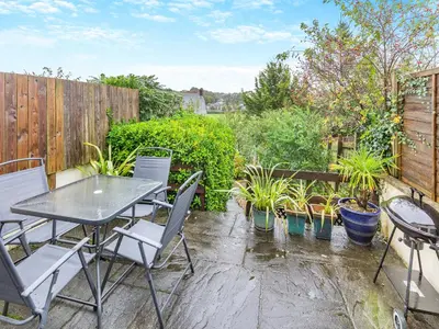 a patio with a table and chairs and potted plants at River View in Wadebridge