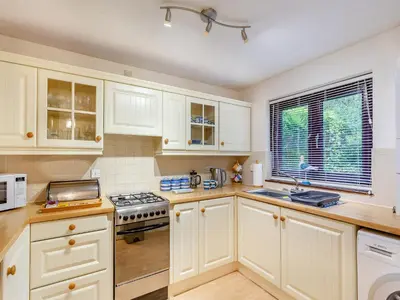a kitchen with white cabinets and a stove top oven at River View in Wadebridge