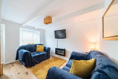 a living room with two blue couches and a tv at Fowey, quaint cottage near sea in Fowey