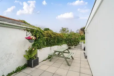 a patio with a green picnic table and plants at Fowey, quaint cottage near sea in Fowey