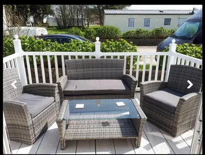two wicker chairs and a table on a porch at Sandydaze in St Merryn