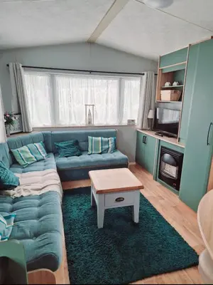 a living room with a blue couch and a table at Sandydaze in St Merryn
