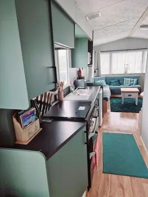a kitchen with a counter top and a living room at Sandydaze in St Merryn