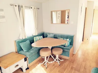 a living room with a blue couch and a table at Sandydaze in St Merryn
