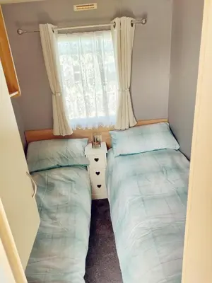 two beds in a small room with a window at Sandydaze in St Merryn