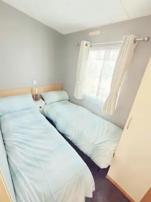 two beds in a room with a window at Sandydaze in St Merryn