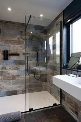 a glass shower in a bathroom with a wooden wall at Uno Carbis Bay - Boutique Luxury Accommodation in Carbis Bay