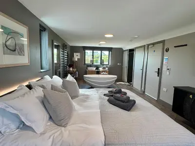 a large white bed in a room with a bathroom at Uno Carbis Bay - Boutique Luxury Accommodation in Carbis Bay
