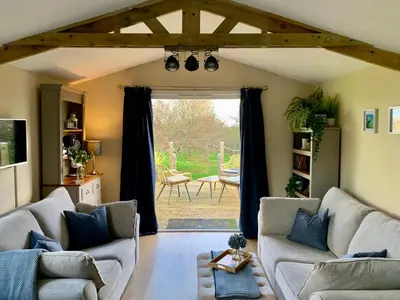 a living room with two couches and a large window at Countryside Cabin in Private Setting in Redruth