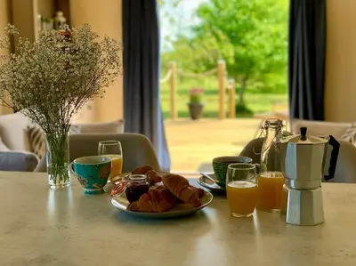a table with a plate of food and glasses of orange juice at Countryside Cabin in Private Setting in Redruth