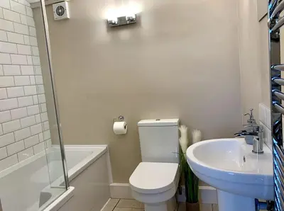 a white bathroom with a toilet and a sink at Countryside Cabin in Private Setting in Redruth