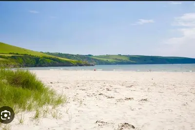 a beach with sand and a body of water at The Lobster Pot in Tywardreath