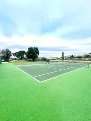 a tennis court with green grass on it at The Lobster Pot in Tywardreath