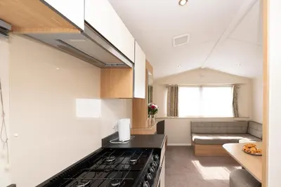 a kitchen with a stove top oven next to a couch at Tencreek Holiday Park in Looe