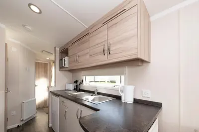 a kitchen with a sink and wooden cabinets at Tencreek Holiday Park in Looe