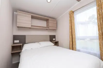 a small bedroom with a bed and a window at Tencreek Holiday Park in Looe