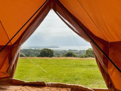an orange tent with a view of a field at Furnished Bell Tent 3 in Carlyon Bay