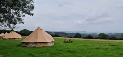 three tents in a field with a picnic table at Furnished Bell Tent 3 in Carlyon Bay