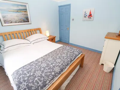 a bedroom with a large bed and a blue door at 5 Tregenna Court in Falmouth
