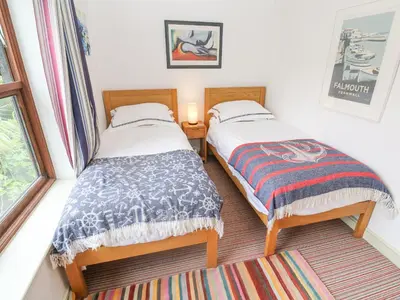 two twin beds in a room with a window at 5 Tregenna Court in Falmouth