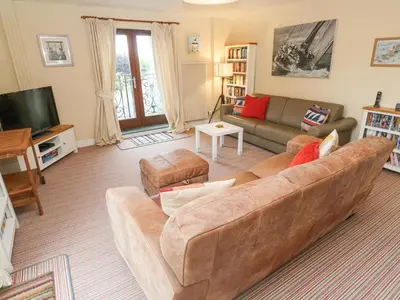 a living room with a brown couch and a tv at 5 Tregenna Court in Falmouth
