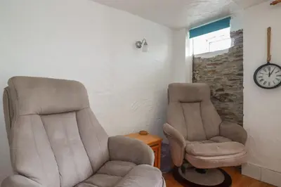 two chairs and a clock in a room at Chy Rani in Portmellon