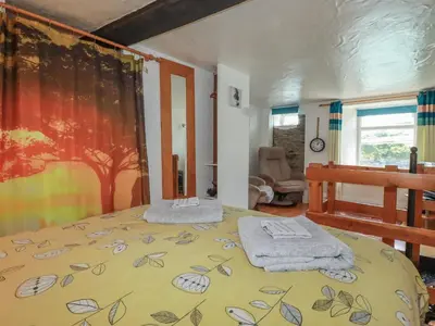 a bedroom with a bed with a blanket on it at Chy Rani in Portmellon
